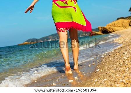 Female in a colorful skirt,walking down the beach.
