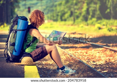 Girl wearing backpack and holding map, waiting for a train.