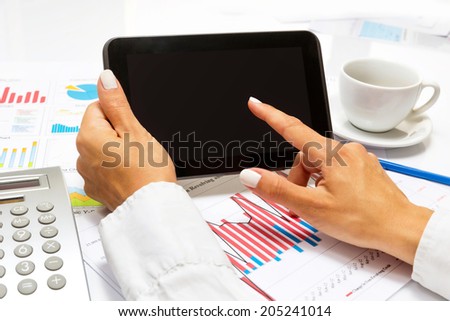 Businesswoman pointing on tablet, inside bright office.