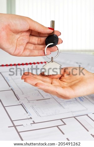 Close up of female architect hand,handing over house key to a customer.