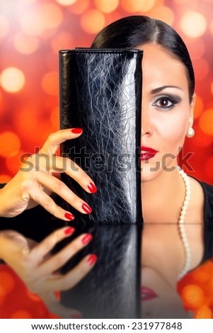 Portrait of a beautiful black hair woman hidden behind black leather wallet with sparkling red and yellow background.