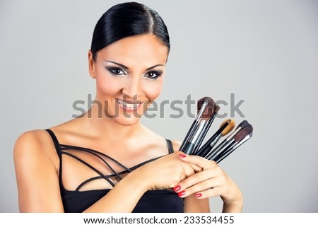 Beautiful smiling black woman girl holding makeup brushes.