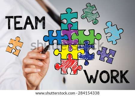 Team work concept. Young business woman drawing assembled puzzle that represent team support and help concept.