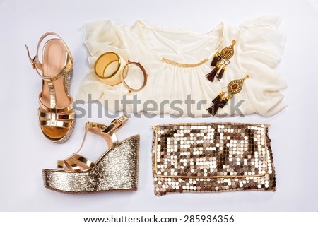 Stylish woman outfit. White summer dress, sandals, golden jewelry and shiny gold purse, isolated on white background.