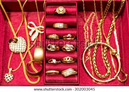 Golden rings,necklace,bracelet and other gold pieces of jewelry,set inside red jewelry box. Top view.