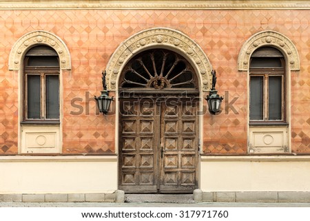 Rustic facade of a building. Double wooden door and windows with arcs.
