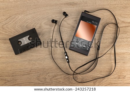 A cassette tape, the old way to listen to music compared to today's modern way to listen to music in a cell phone.