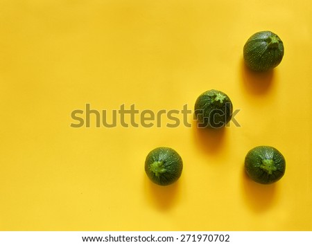 Green round courgette triangle on a yellow background with copy space