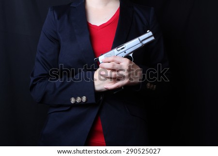 female hand holding gun with a black background