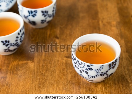Teacups filled with tea on a wooden table.