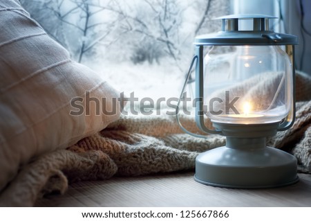 lantern and pillows on windowsill with winter view lantern and pillows on windowsill with winter view