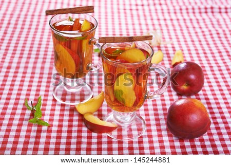 glass mugs with peach tea on red and white checked cloth