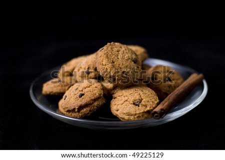 plate of cookies with cinnamon stick on black background