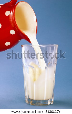 milk pouring in glass on blue background