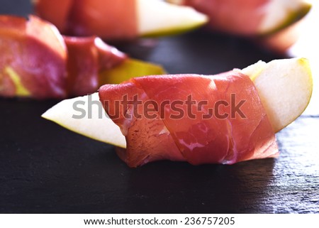 sliced pear with smoked ham on dark backdround