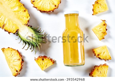 ripe pineapple slices and juice over white background. top view