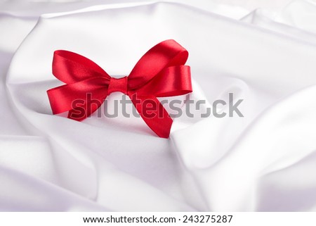 Red ribbon satin bow on the nice white silk