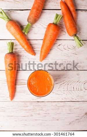 Glass of carrot juice and carrots on the white table