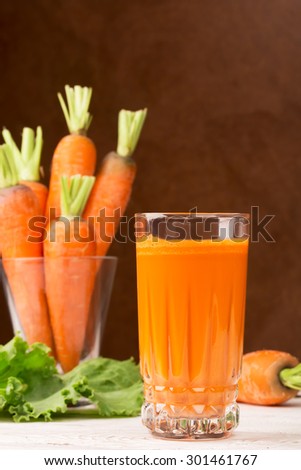 Glass of carrot juice and carrots on the white table