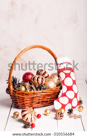 Christmas basket with red and golden ornaments, fir-cones on a wooden table (with copy space)