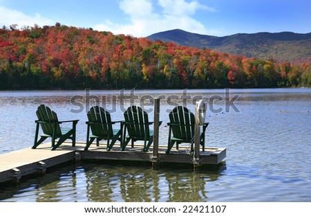 Adirondack chairs on a swim dock, on a peaceful lake in the Adirondack State Park in New York State.