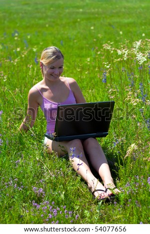 Beautiful young girls in nature using a computer.