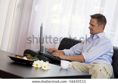 Man sitting on couch using laptop computer at home.