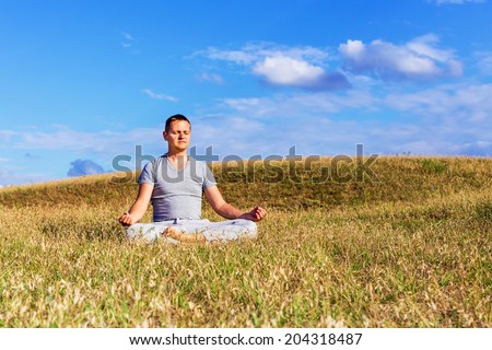 The peaceful scenery of a man meditating in the lotus position.
