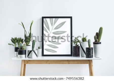 The modern room filled a lot of plants in different handmade design pots on the brown wooden table. Mock-up with a poster frame.