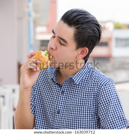 Young man eating  hamburger