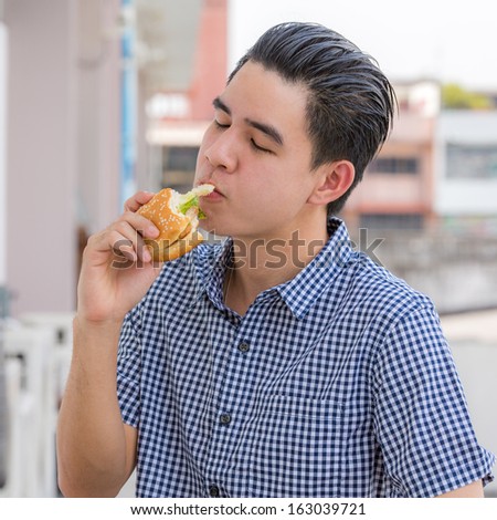 Young man eating  hamburger