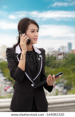 Portrait of a confident business woman talking on phone and hold tablet