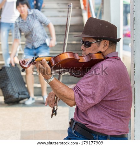 BANGKOK - FEB 22:Man plays violin in Jatujak market,the famous weekend market on Feb 22, 2014 in Bangkok,Thailandis one of the destination of foreigners Only open Saturdays and Sundays