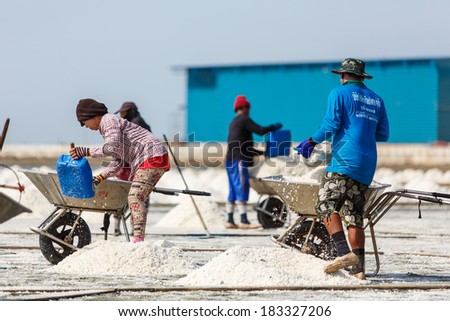 SAMUTSAKORN,THAILAND -APRIL 15: The workers are moving the raw salt to the store at Rama II road on April 15,2013 in Samutsongkram, Thailand. Samutsongkram is a big salt production area of Thailand