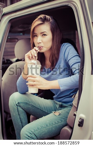 Asian girl drinking iced coffee in car and looking at the camera
