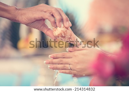 hand of a bride receiving holy water from elders in thai culture wedding ceremony, process color