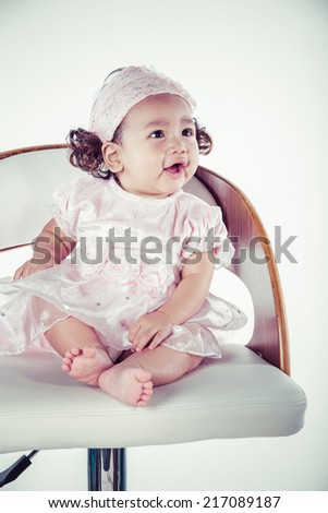 Portrait of the six month baby on the chair on white background, process color