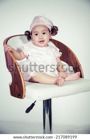 Portrait of the six month baby on the chair on white background, process color
