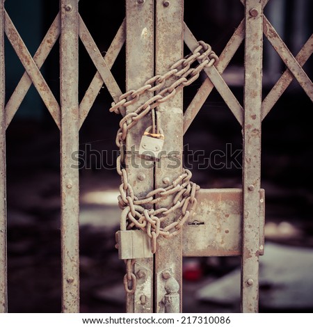 rusty chain and master key locked on grunge iron gate, process color