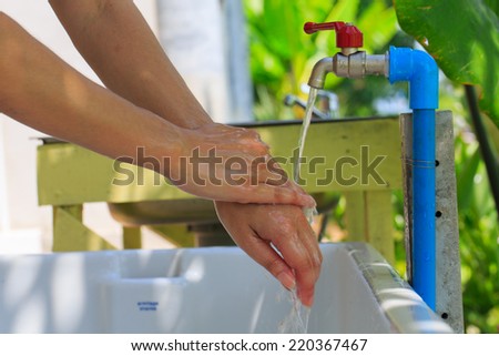 Close-up of human hands being washed under stream of water from tap