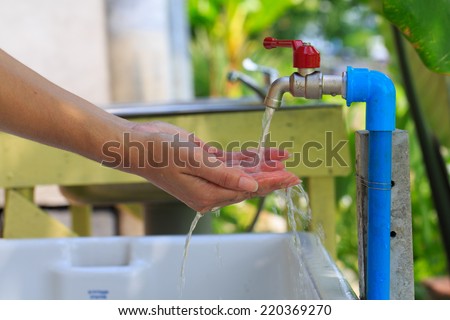 Close-up of human hands being washed under stream of water from tap