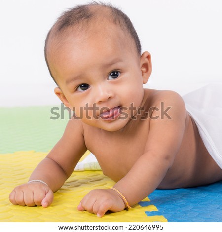 Happy cute 5 month old Asian baby boy with short black hair on rubber floor