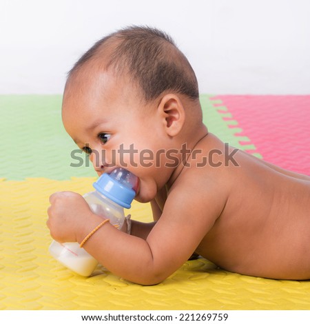 Happy cute 5 month old Asian baby boy with drinking milk on rubber floor