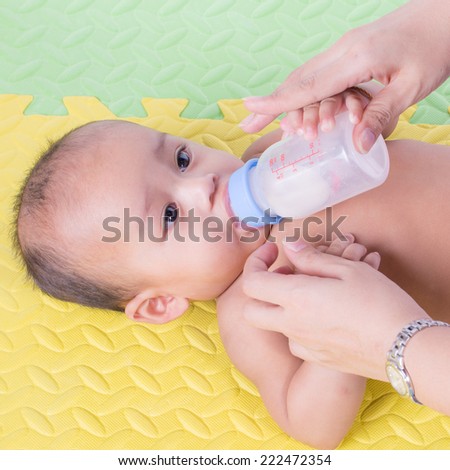 Happy cute 5 month old Asian baby boy with drinking milk on rubber floor