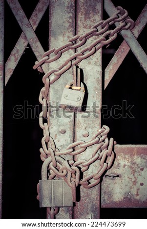 Close -up rusty chain and master key locked on grunge iron gate