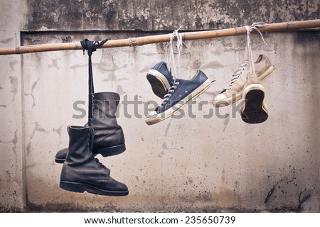 pair of old sneakers and old boot hang on bamboo, process color