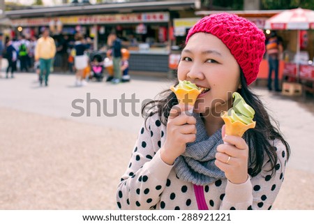 Asian woman with wool hat eating ice cream, green tea two cone at Osaka Castle. japan, process color