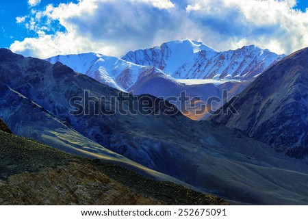 Rocky landscape of with ice peaks in background , light and shadow in high altitude, Ladakh, Jammu and Kashmir, India