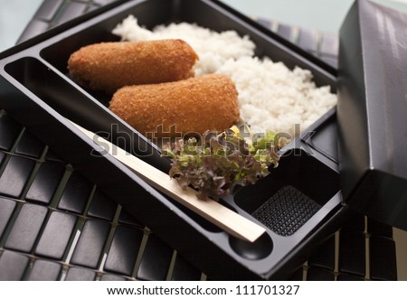japanese food with rice in a take away box, spring rolls