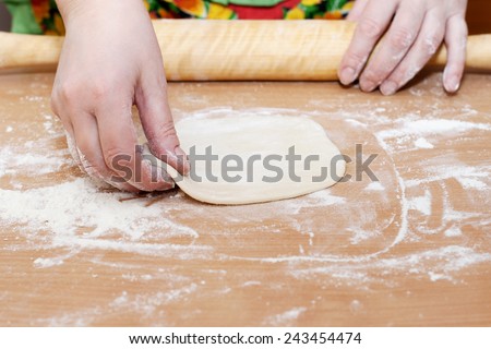 female hand holding a circle of dough kitchen table
